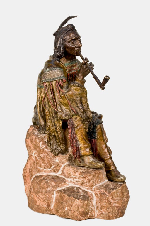 Austrian poly-chromed and bronze sculpture of an Indian sitting atop a rock smoking a peace pipe by Carl Kauba. The sculpture is signed, Austria.