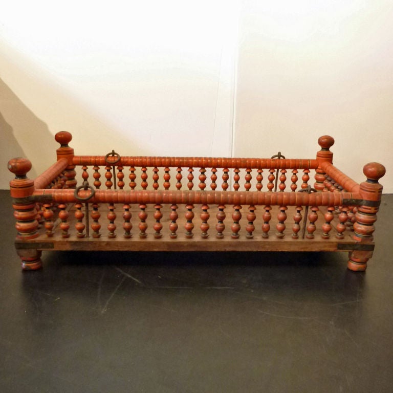 Swinging baby cradle from South India made of hardwood planks and turned wood posts with natural lacquer paint. Makes a great dog or cat bed.