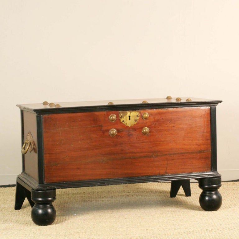 Indo-Dutch colonial storage trunk of solid single plank construction in jackfruit, the lid and top of base have ebony trim. The inside of the trunk has very large brass hinges with pierced details. The trunk rests on two trestles each with one large