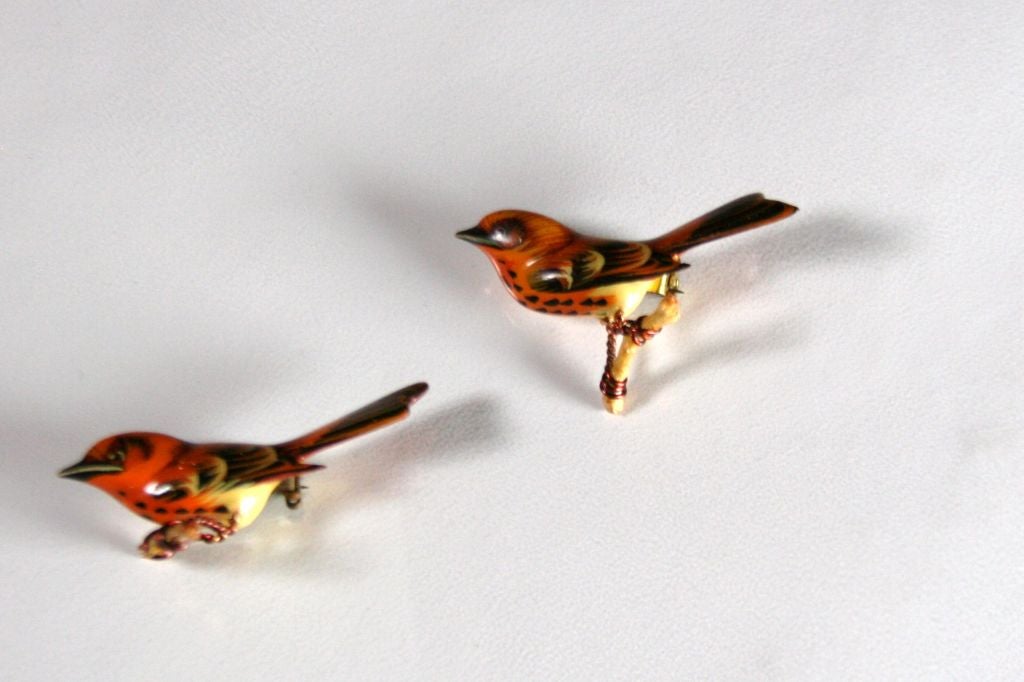 Life-like miniature bird brooches hand carved from hardwood, hand painted then lacquered by Japanese internment camp prisoners in Arizona during WWII. The wire feet are twisted around natural branches. Pin backing.