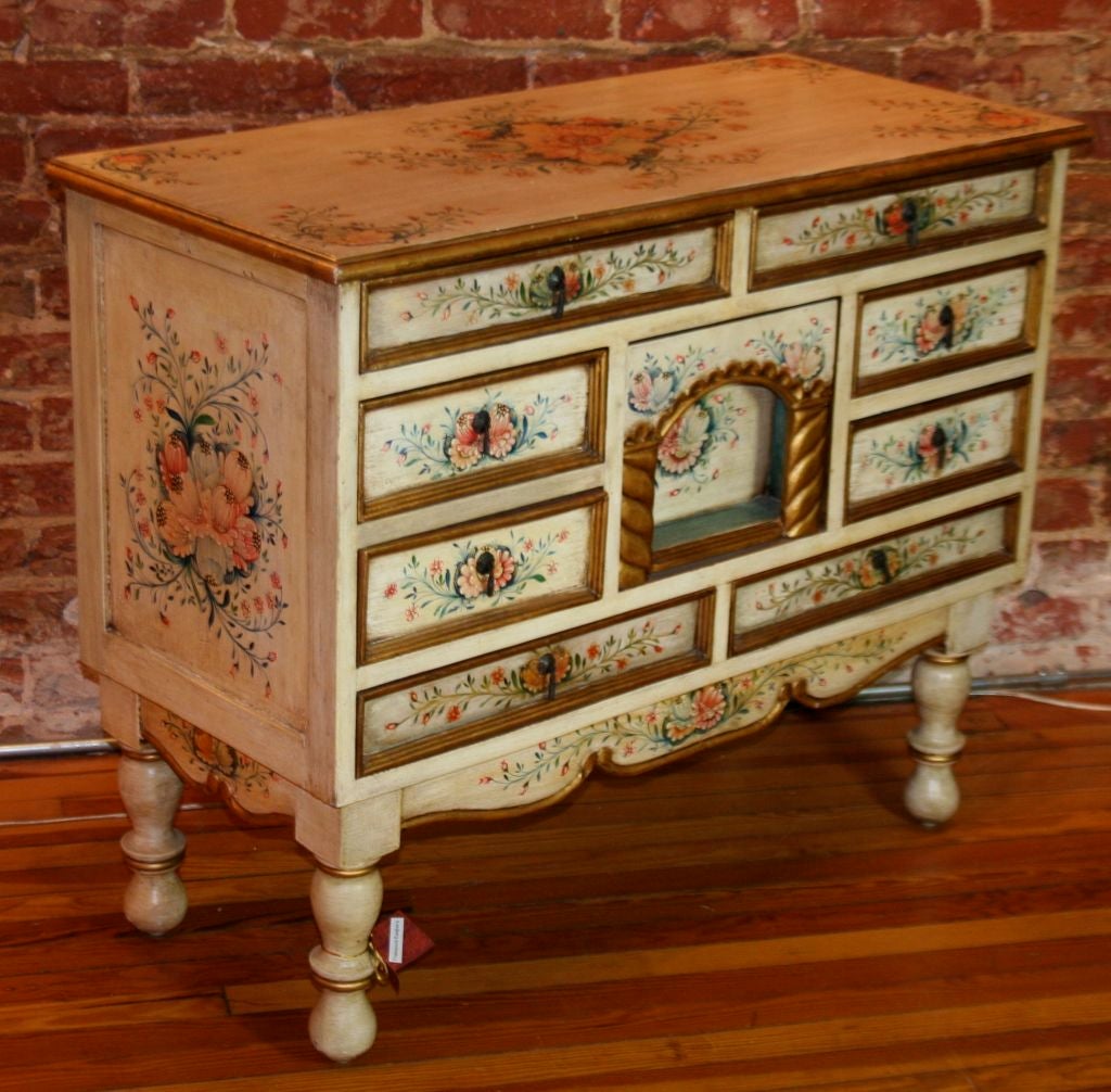 Romantic nine-drawer hand-painted Central European chest with shadow box and bun feet. The indented miniature theatre pocket drawer in center with handle adds a romantic touch to this lovely floral commode.