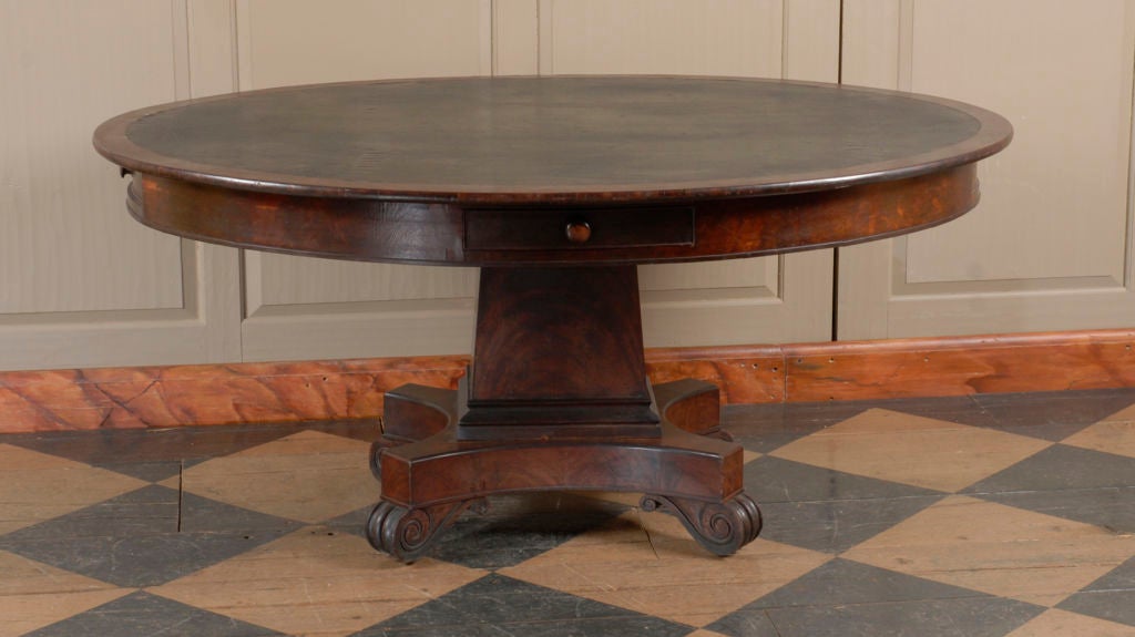 The large molded oval top still retains its original black oil cloth covering. The top is above a molded apron which is fitted with four drawers at each corner.  Two of these drawers are locking. The tapered rectangular column with molded base is