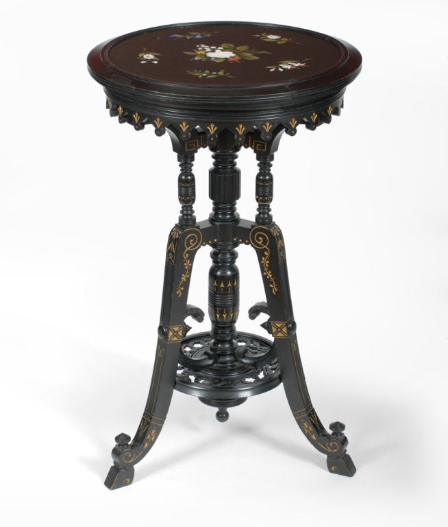 This exuberant Eastlake stand has a highly decorated tripod base with a variety of turnings, carvings and gilt highlights.  The bottom of the saber legs are joined with a circular disk fitted with a pierced and floral carved fretwork.  The inlaid