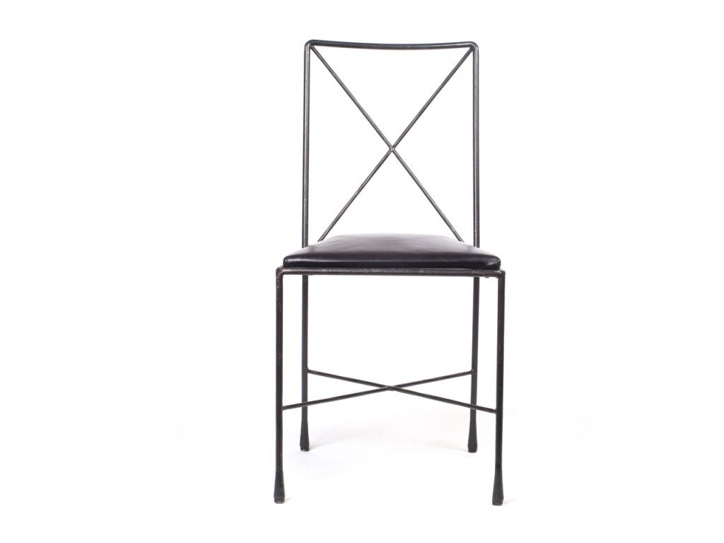 A set of four superfine black wrought iron dining chairs with black leather seats. Made by Avard New York