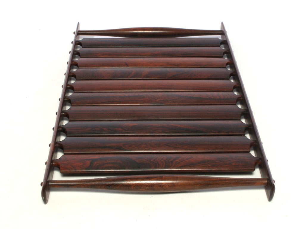 A rosewood serving tray, comprised of ten radius-backed slats with fingered tenons mortised through the oval-section siderails, flanked by swollen dowel handles (from the Dansk 