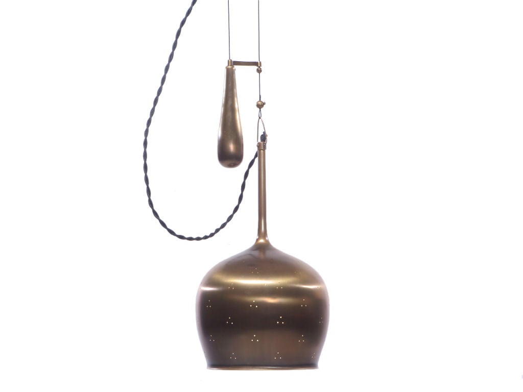 A patinated brass pull down ceiling lamp with a perforated shade in the form of an inverted wine glass.