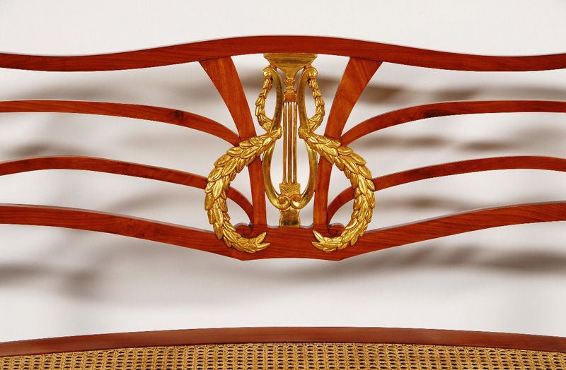 Solid cherry, with carved appliqué in gesso and 23-karat gilt polychrome with restored cane seat.