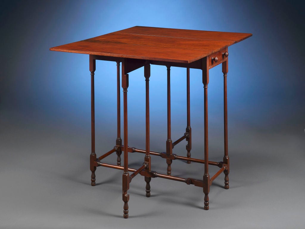 This exceptionally rare and delicate mahogany table displays Tiffany Studios’ vision of the distinctive Arts & Crafts style. Set upon six thin legs, the striking drop leaf design features two collapsible leaves flanking a single drawer. When fully