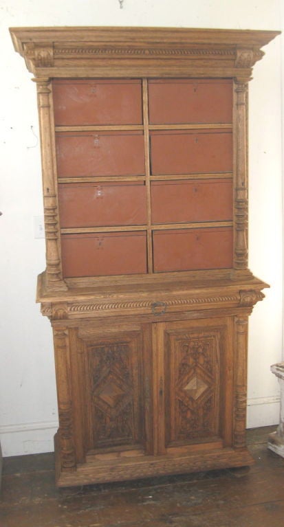 This unusual two tier oak storage cabinet has been bleached to a light finish. There are eight upper doors. Unlock the small latch on each and the doors fold down to reveal small storage spaces.(see image #6) Note all the decorative hand carved