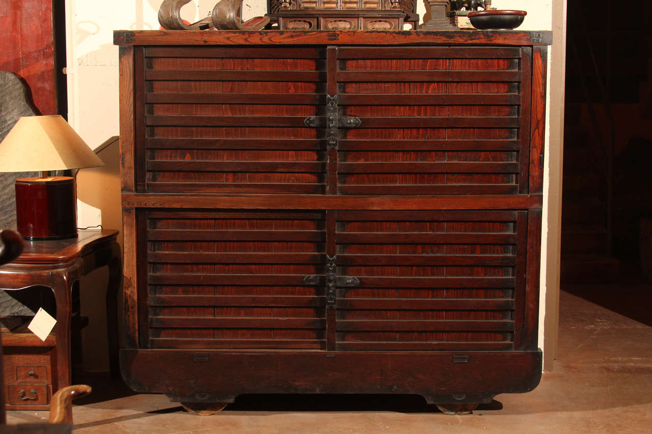 Japanese kuruma dansu (wheel chest) of keyaki (Elm wood) with two sets of sliding panels. The panels open to reveal large interior compartments.  With original iron hardware. A good example with original finish and dark patina. Kuruma-dansu were