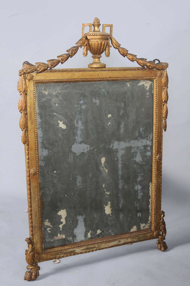 Antique mirror, having a rectangular frame of giltwood, its cockbeaded border, surmounted by a fluted urn, flanked by swags of laureling,  raised on paw feet.