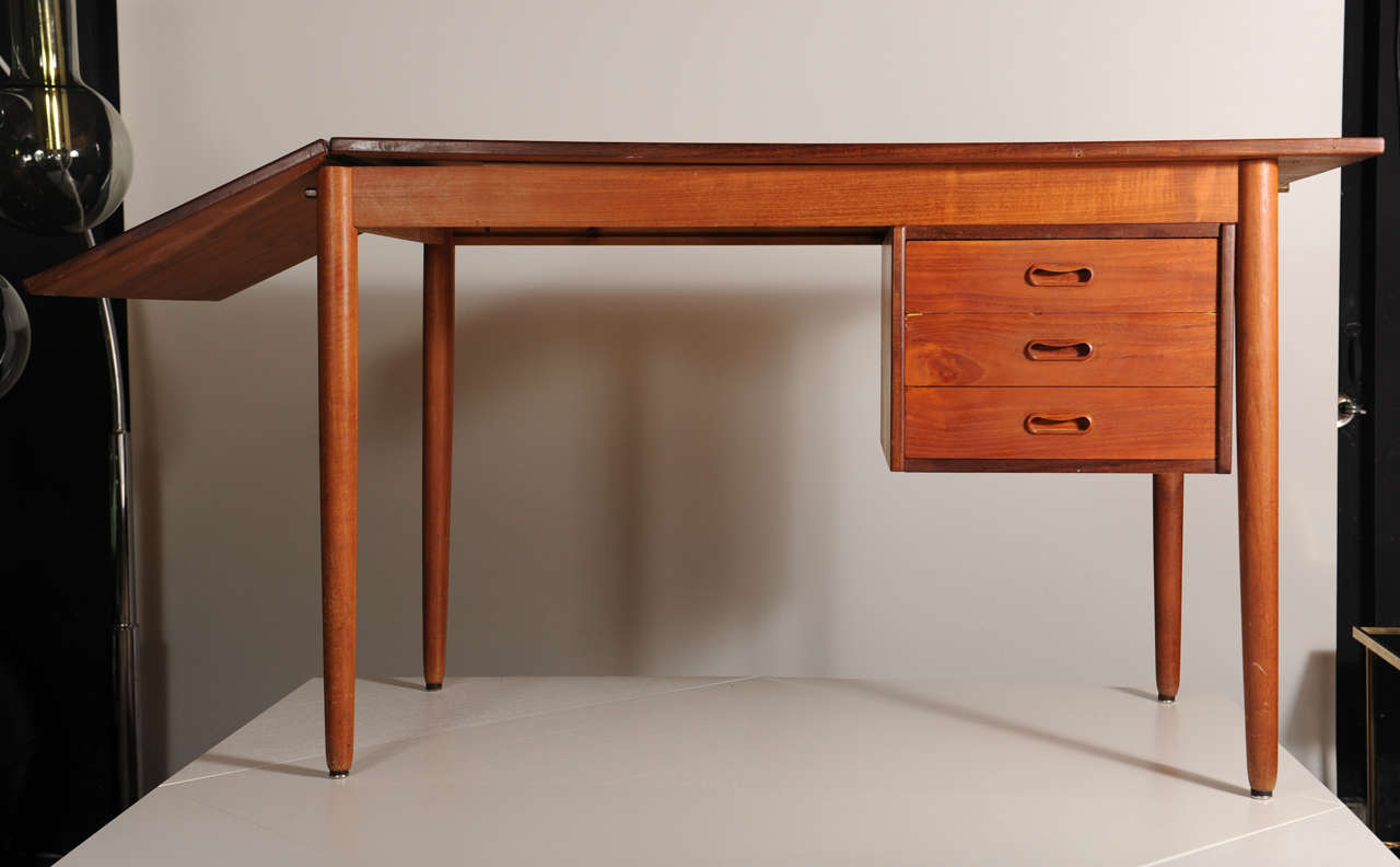 Danish design from the 1960's this wonderfully made desk. Special feature is the drawer compartment with a bookshelf in the back that slides to each side according to which wall you want to put the desk. Also the desktop is extendable by a drop leaf