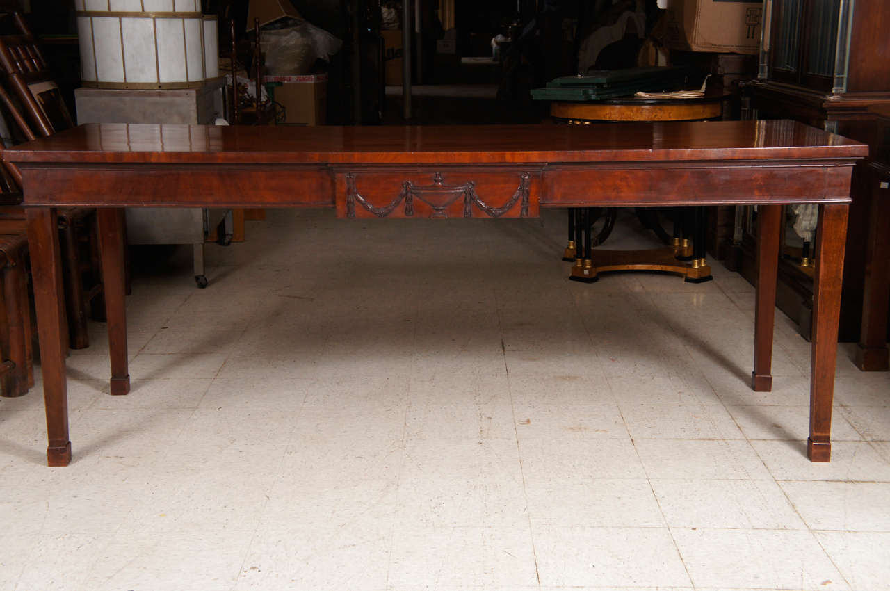 This large-scale mahogany table done in the Georgian style was made circa 1900. Retaining its original finish with a fine old patina the large board top shows a choice grain selected mahogany which matches the scale of the top. The apron is centered