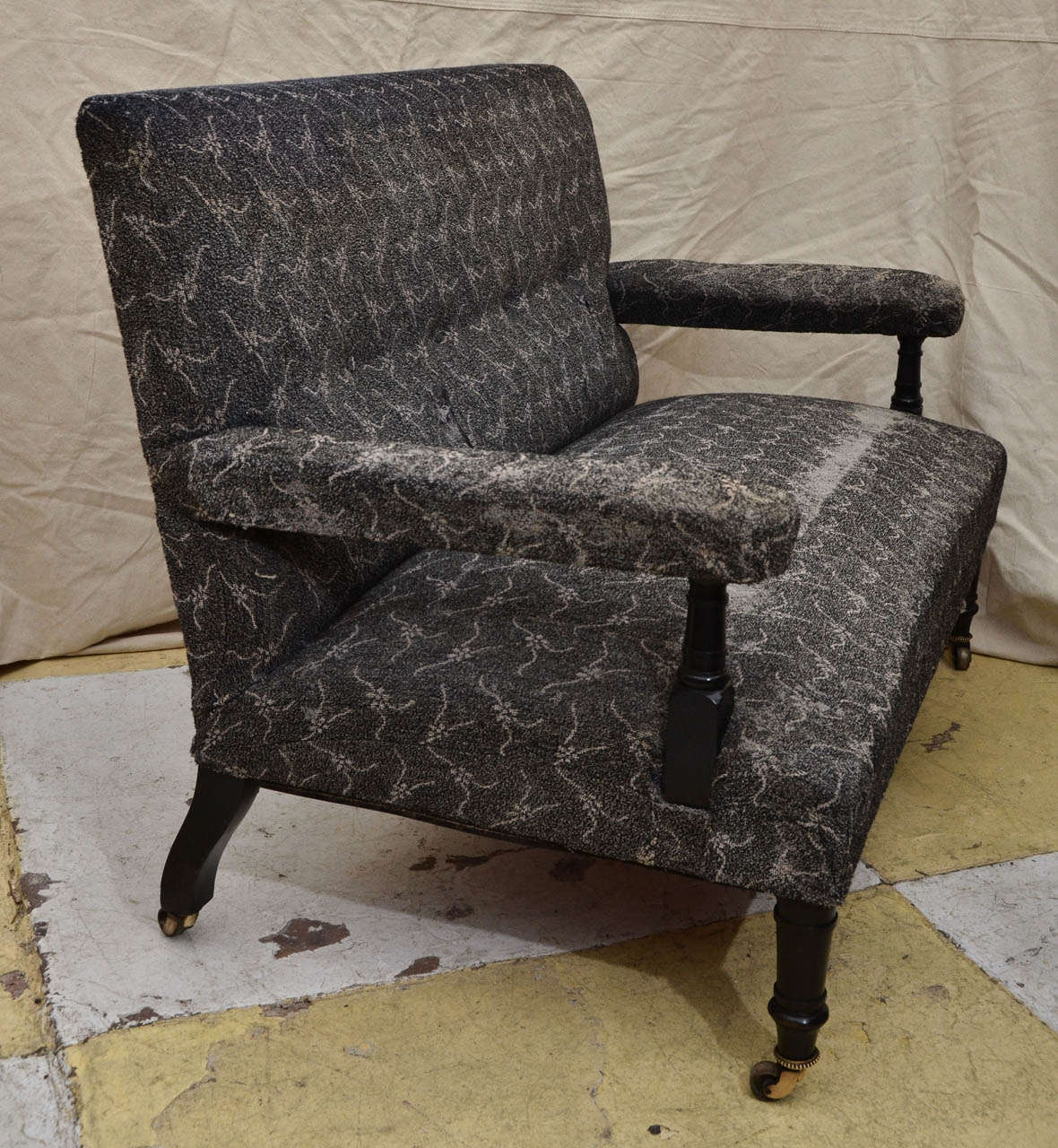 English ebonized Aesthetic Movement platform arm settee with button tufted back above a lower lumbar roll at base of the back. The front legs terminate with brass castors having a beaded bessel. The settee is an unusual design -- similar to a
