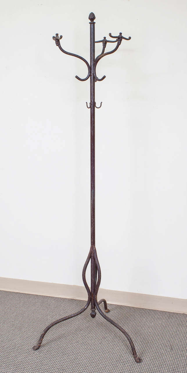 A handsome and sturdy cast and wrought iron halltree featuring three double and six single hooks on a central cylindrical post with pineapple finials top and bottom.  The whole in old barn red paint.