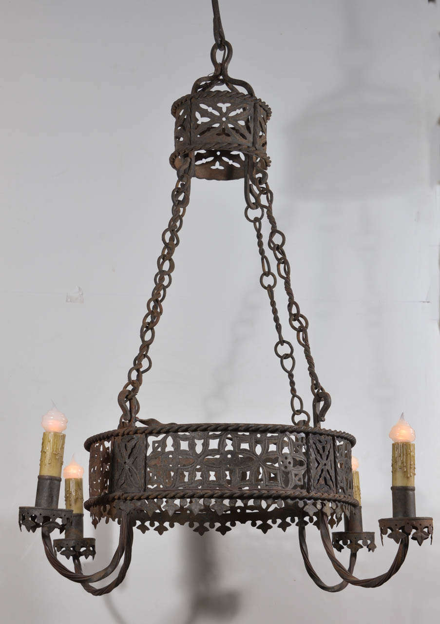 Newly-wired late 19th century iron chandelier with an intricately reticulated round body encircled by twisted iron bands at the top and bottom with gracefully curved twisted iron arms that support bobeche cups. Four decorative iron chains connect