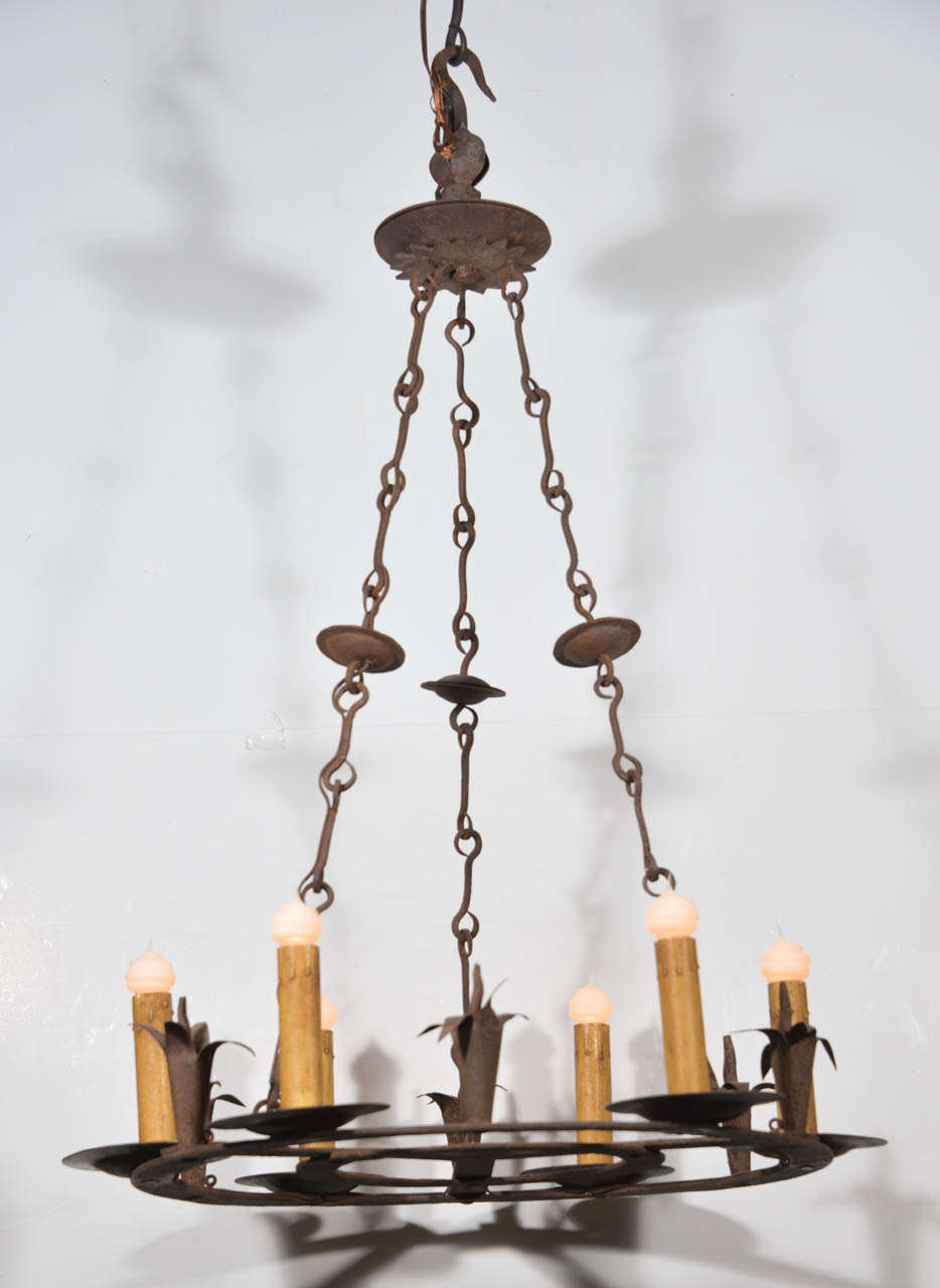 Antique wrought iron chandelier with a fine patina, newly-wired with six medium-base size lights atop a flat round body, suspended from a gatherer by three lengths of decorative iron hook-chain.