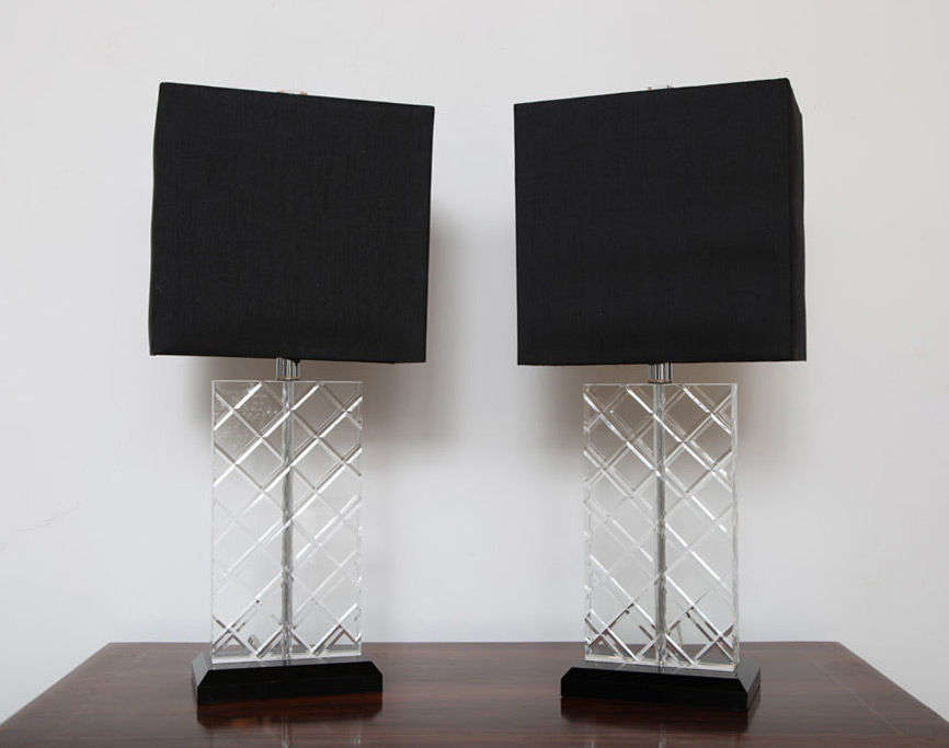 Heavy pair of lead crystal lamps with black lucite bases.  Crystal base has criss-cross etching throughout front and back adding a certain jeweled look to the lamps in the light.  Black silk with metallic gold interior lampshades included.  Length