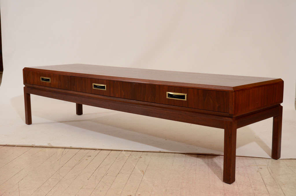 Handsome walnut coffee table with nice graining and brass pulls. Three drawers are aligned across the front. Please contact for location.
