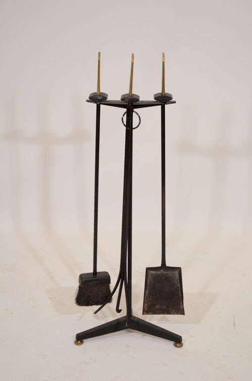 Classic fireplace tool set designed by Donald Deskey for Bennet. The iron tools are each topped with a sculptural brass finial. Please contact for location. 