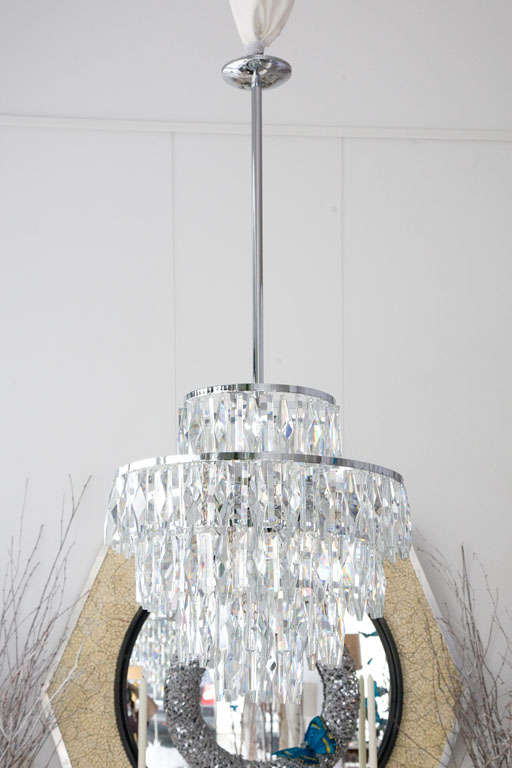 This remarkable and glamorous chandelier from the 1960's is stunning.  Featuring five tiers of alternating faceted Austrian crystals hanging from telescoping chrome plated rings will create a beautiful mood in any room.