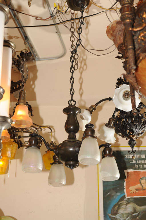 This richly patinated four arm chandelier has simple elegance and classic design.  The four shades are original 1920s carnival glass which shows off the wonderful irridescence of this type of glass.  Can be shortened to your liking.