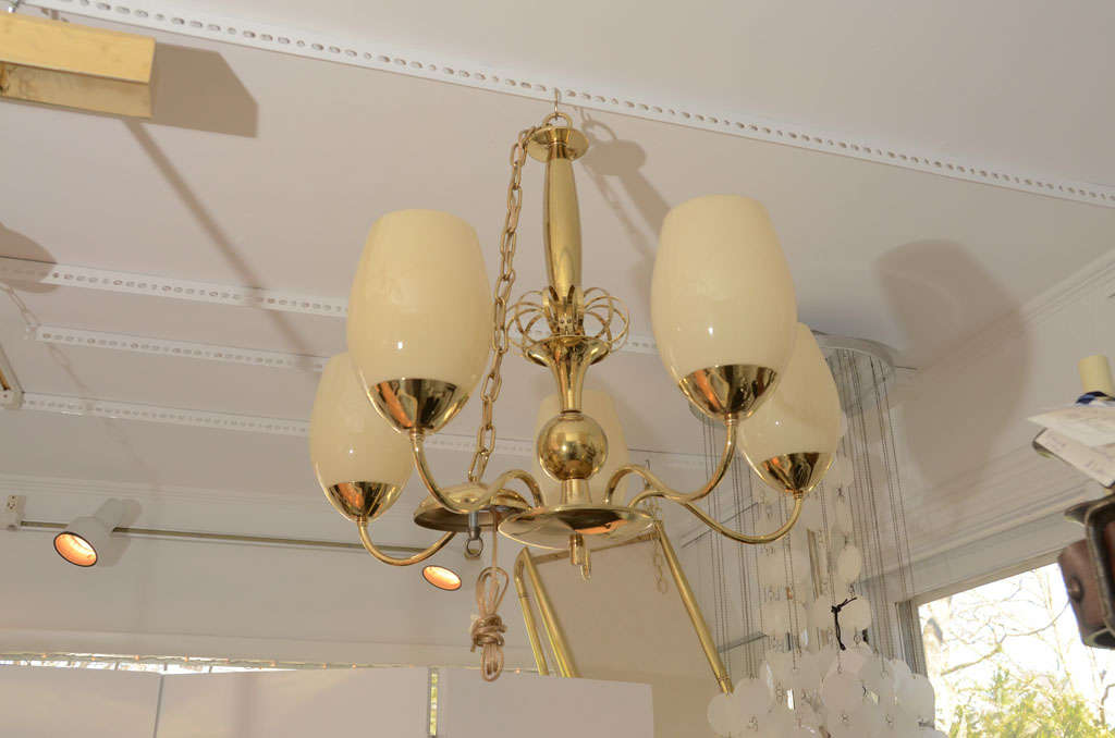 Five-arm brass chandelier with opaque glass globes.