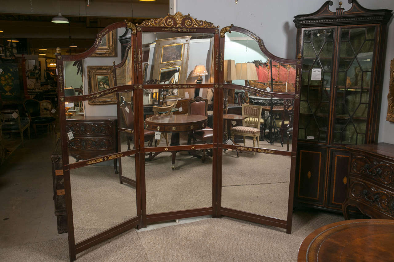 This wonderful and large room divider or screen has nine mirror panels framed in a fine mahogany grained wood decorated with bronze mounts. This highly functional screen is extremely decorative and would fit in any room with most all interiors. This