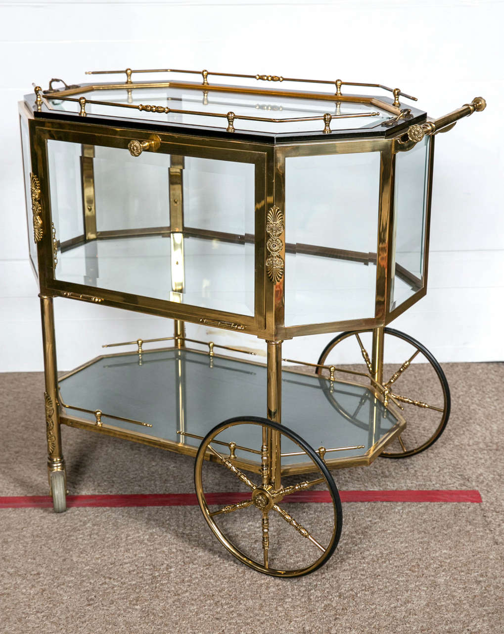 Beveled glass bronze tea wagon or serving cart. This wonderful Hollywood Regency style cart has small wheels in front with large wheels in back supporting a brass and bronze-mounted column form set of legs. The lower brass galleried glass shelf