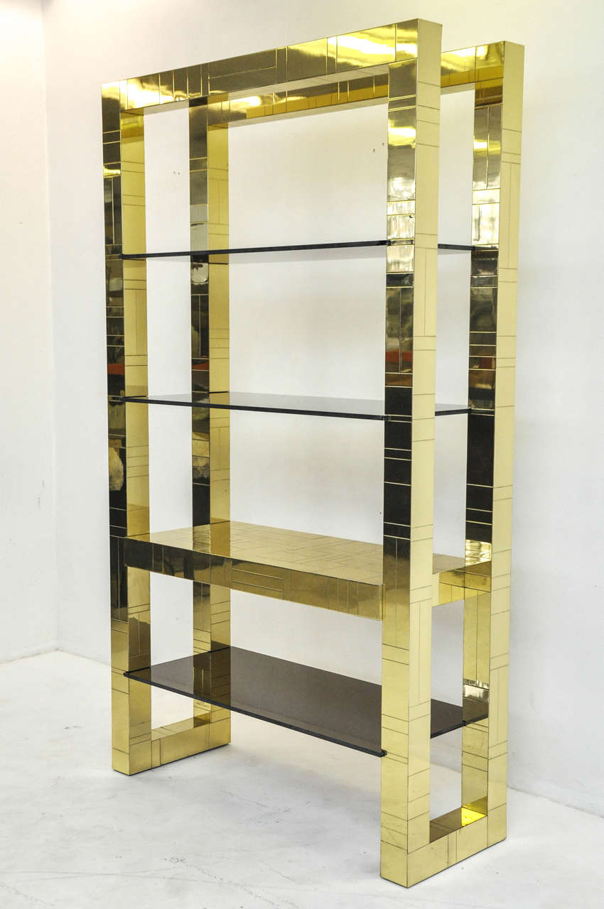 Brass clad étagère by Paul Evans. Brass is in excellent condition with smoked glass shelves. Signed 