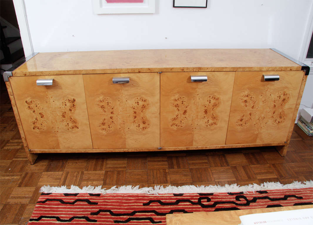 A long, four-door cabinet (perfect as a sideboard or dresser) designed by designer Irving Rosen for PACE. The top, sides and front with gorgeous exterior in a light burled wood - possibly maple or birch - with chrome-plated metal accents on each