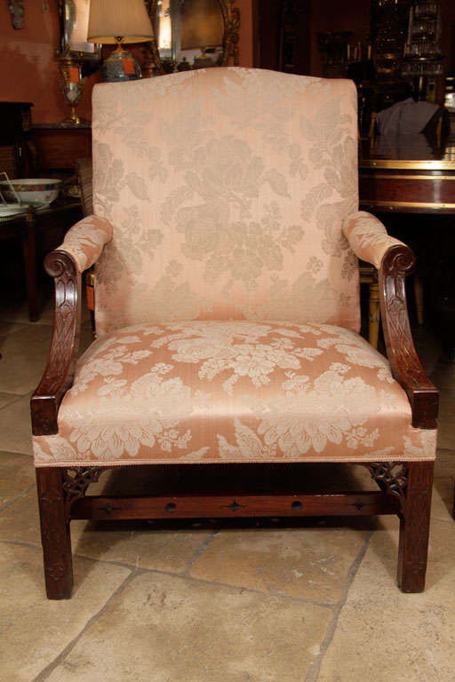 Fine pair of George III mahogany Gainsborough arm chairs with blind fret carved supports, openwork brackets and pierced Gothic stretchers. In the manner of Thom. Chippendale.
