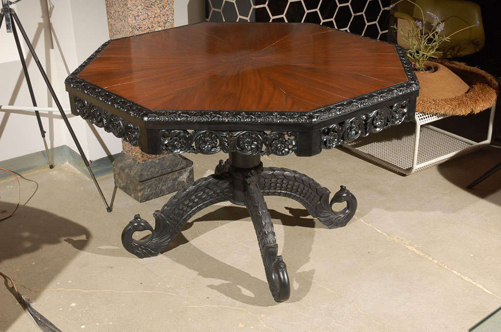 An ebonized and walnut center table with peacock form splayed supports