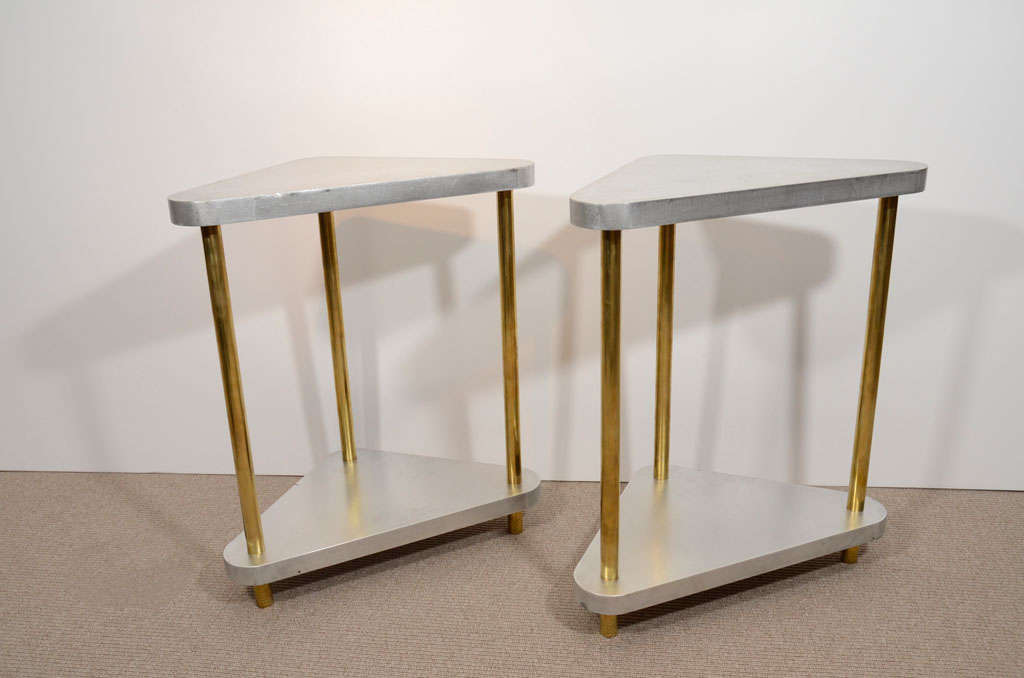 Triangular satin steel tables with three tubular brass uprights.