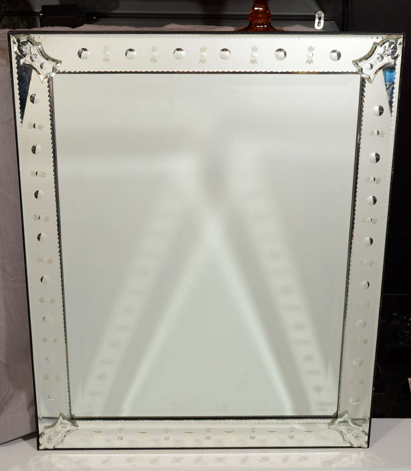 Venetian mirror with reverse etched and convex circle designs. The mirror features hand beveled and chain beveled mirrored borders and has styized Venetian mirrored fittings and rosettes.  Excellent scale for an entry way, hallway, or powder room.