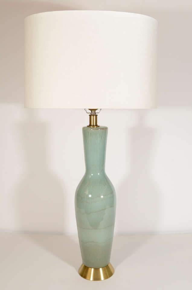 Pair of hand blown ceramic lamps with modern urn design in gradient seafoam glaze, and with brushed brass bases and fittings. Shown with custom oval shades in ivory linen.