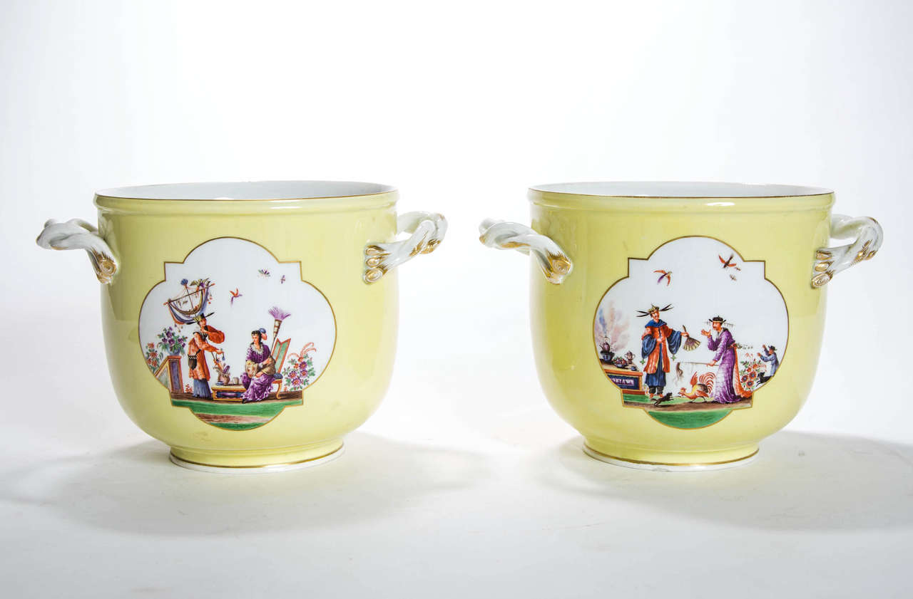 A pair of Meissen yellow ground Jardinieres decorated with chinoiserie figure scenes and twist-branch handles, blue crossed swords dot mark.