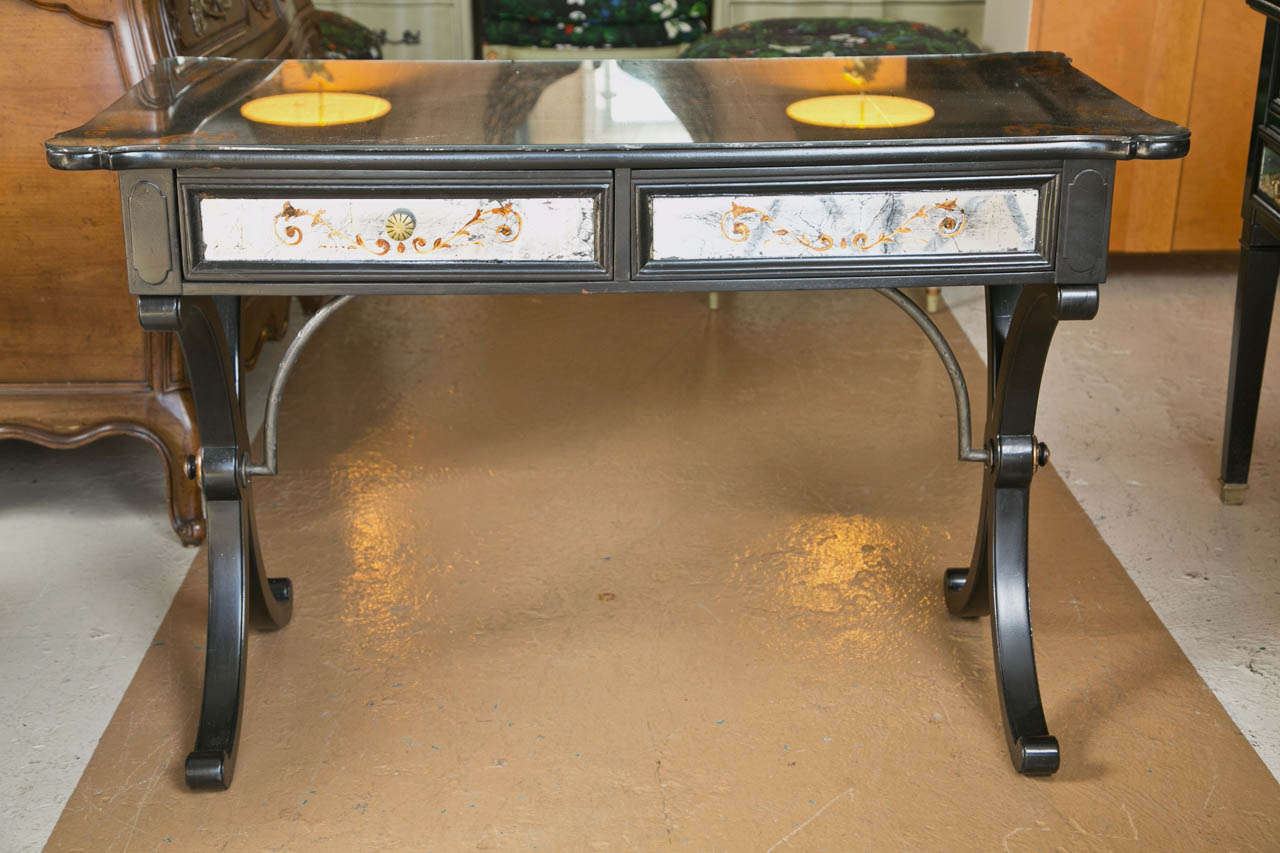 A finely constructed French desk. The curved C-shaped inverted legs supported by a metal undercarriage. The top verre églomisé decorated with leafs and vine design. The double drawers having verre églomisé panels as well as the sides and reverse of