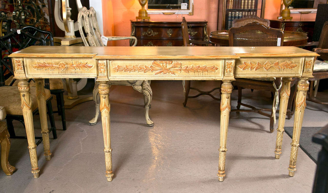 French distress painted console table in the style of Louis XVI, circa 1940s, the beveled top over a narrow frieze decorated with acanthus carving, raised on fluted tapering legs ending in toupie feet. By Jansen.