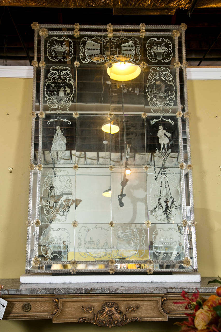 A monumental vintage Venetian mirror, the rectangular looking glass surmounted in beautiful eglomise glass panels decorated with etched patterns of figures, scrolls, and flower baskets; small glass Florettes attached between each panel and