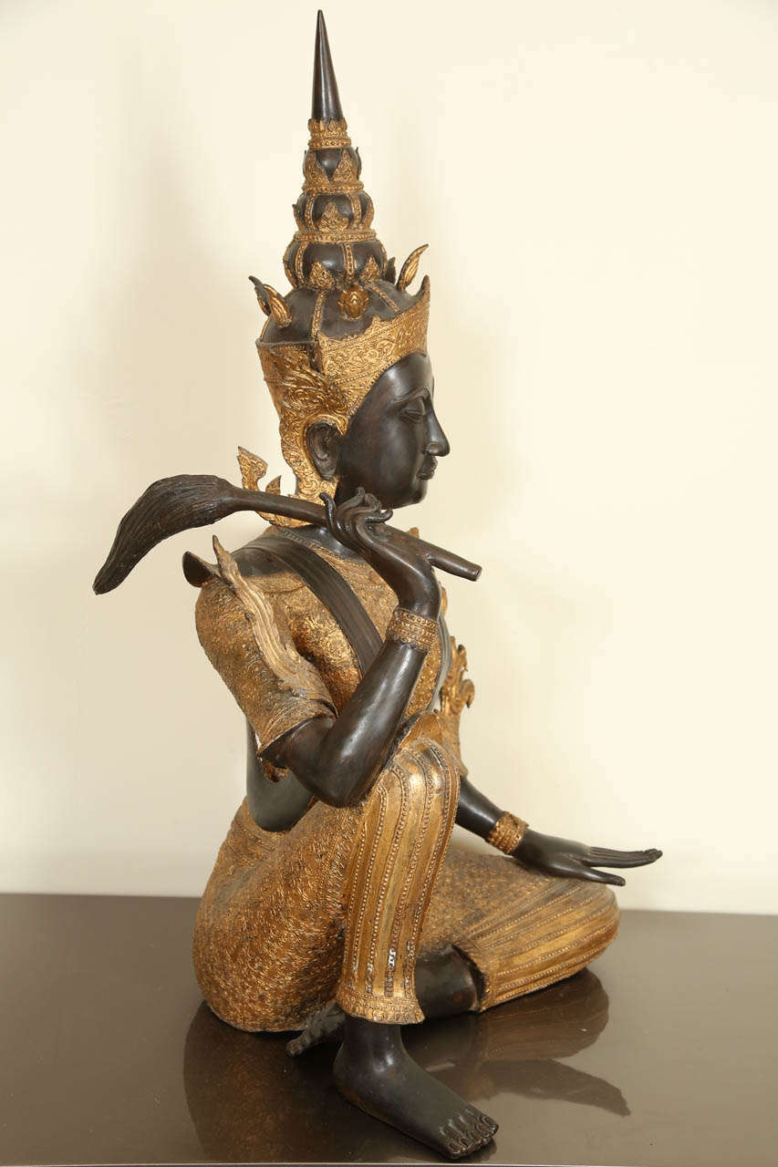Magnificent beautiful Thai bronze statue of a deity holding a flail.  The tiered crown and elaborately detailed costume are set off by gilding.
The quality of the metalwork is very high.