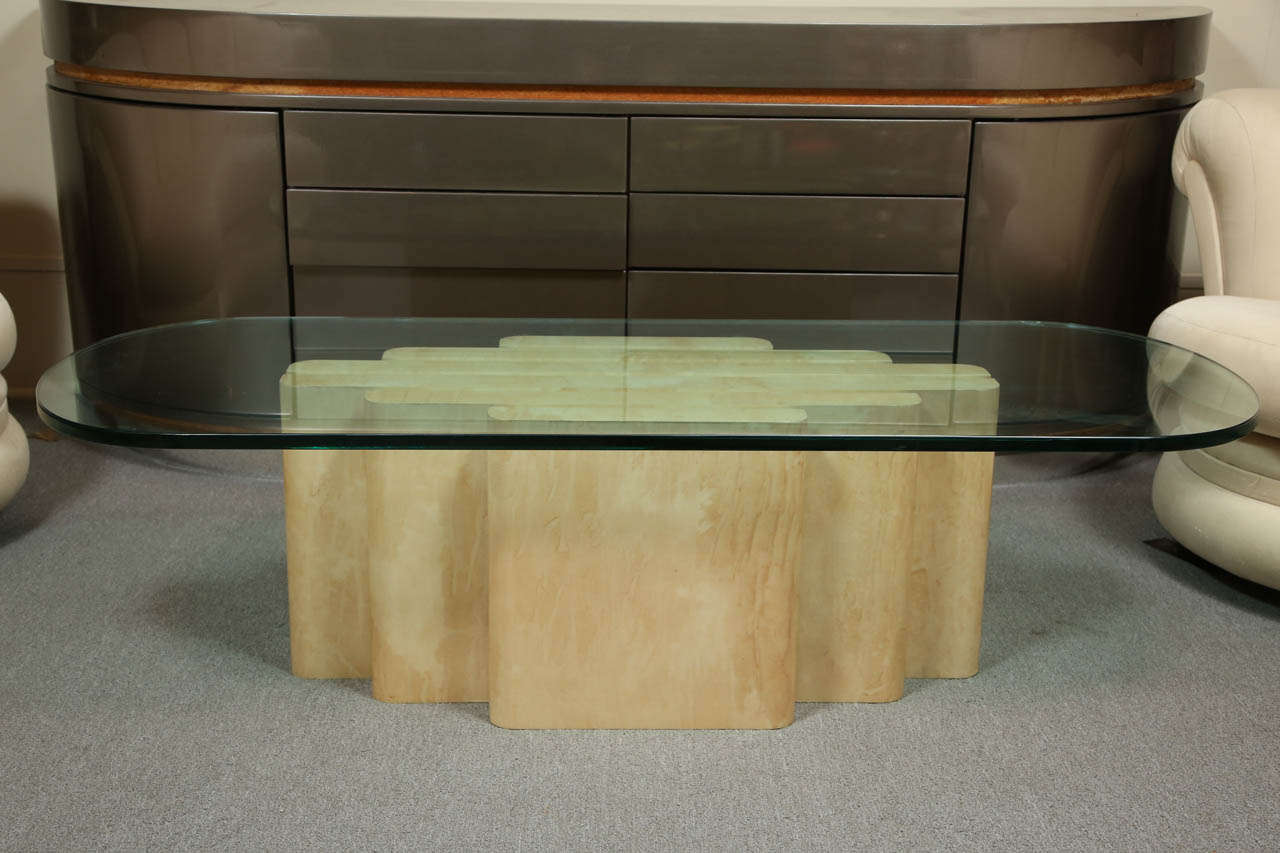 Coffee table finished in lacquered goatskin with brass strip accents by Steve Chase.
The table has a glass top with broadly rounded corners.