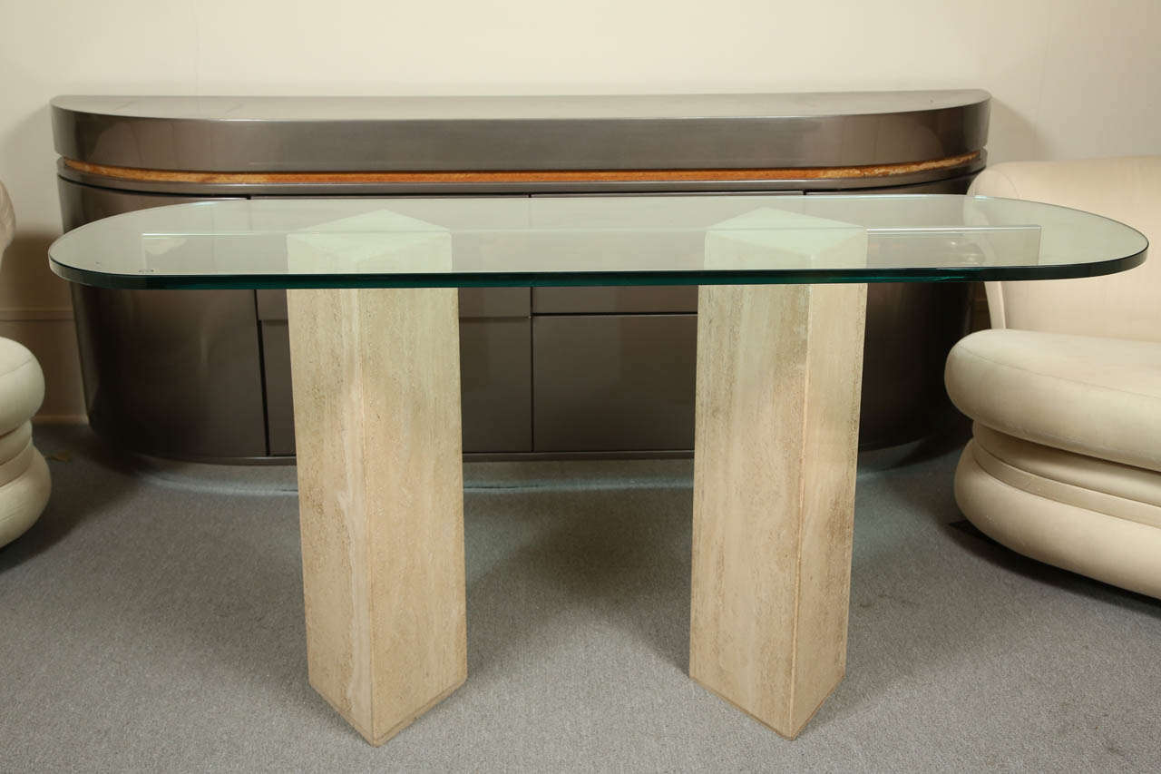 Stylish console with travertine pylons and a brass bar which supports the glass top.