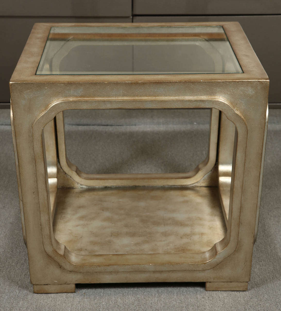 Elegant side table by James Mont.
The wooden table has a glassed silver leaf finish and an inset glass top.
