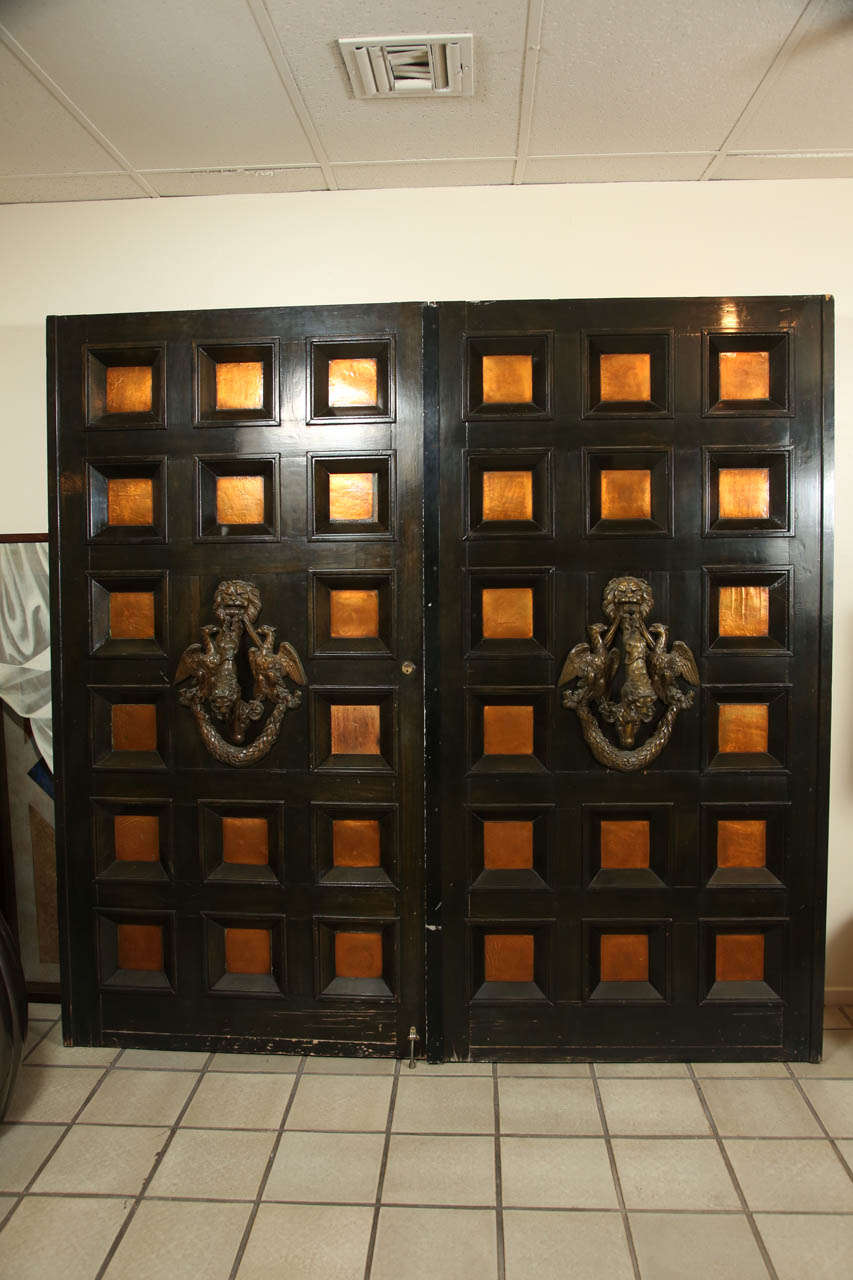 Magnificent pair of paneled doors from the estate of the actor Laurence Harvey in the Las Palmas district of Palm Springs CA.
The doors have deep paneling with insets of burnished and lacquered copper.
The elaborate bronze knockers have lions