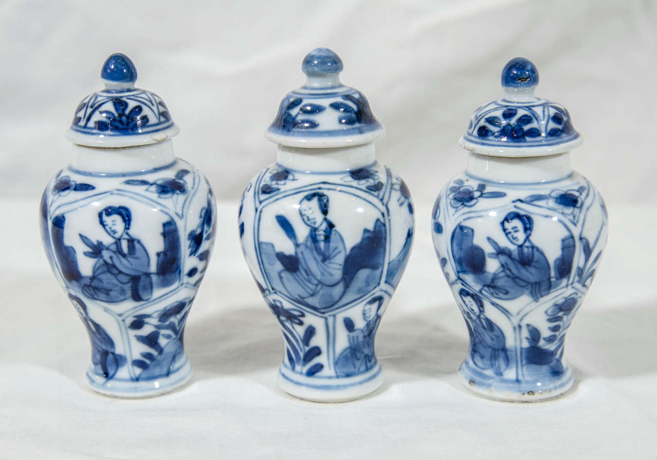 Each vase decorated in underglaze cobalt blue with traditional lappet shaped panels showing a young woman alternating with panels showing flowering plants.