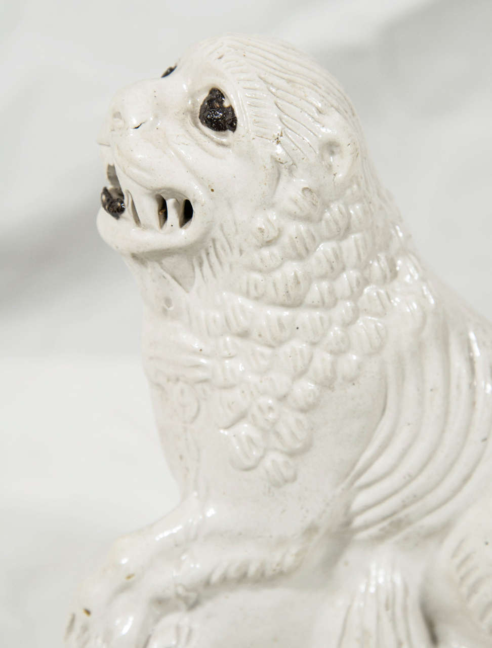  This salt glaze figure of a lion was made in England in the mid-18th Century circa 1760.  The figure has personality. The figure was slip-cast and has sharp definition in the molded mane, teeth, and ribs. The notable eyes and tongue were made using