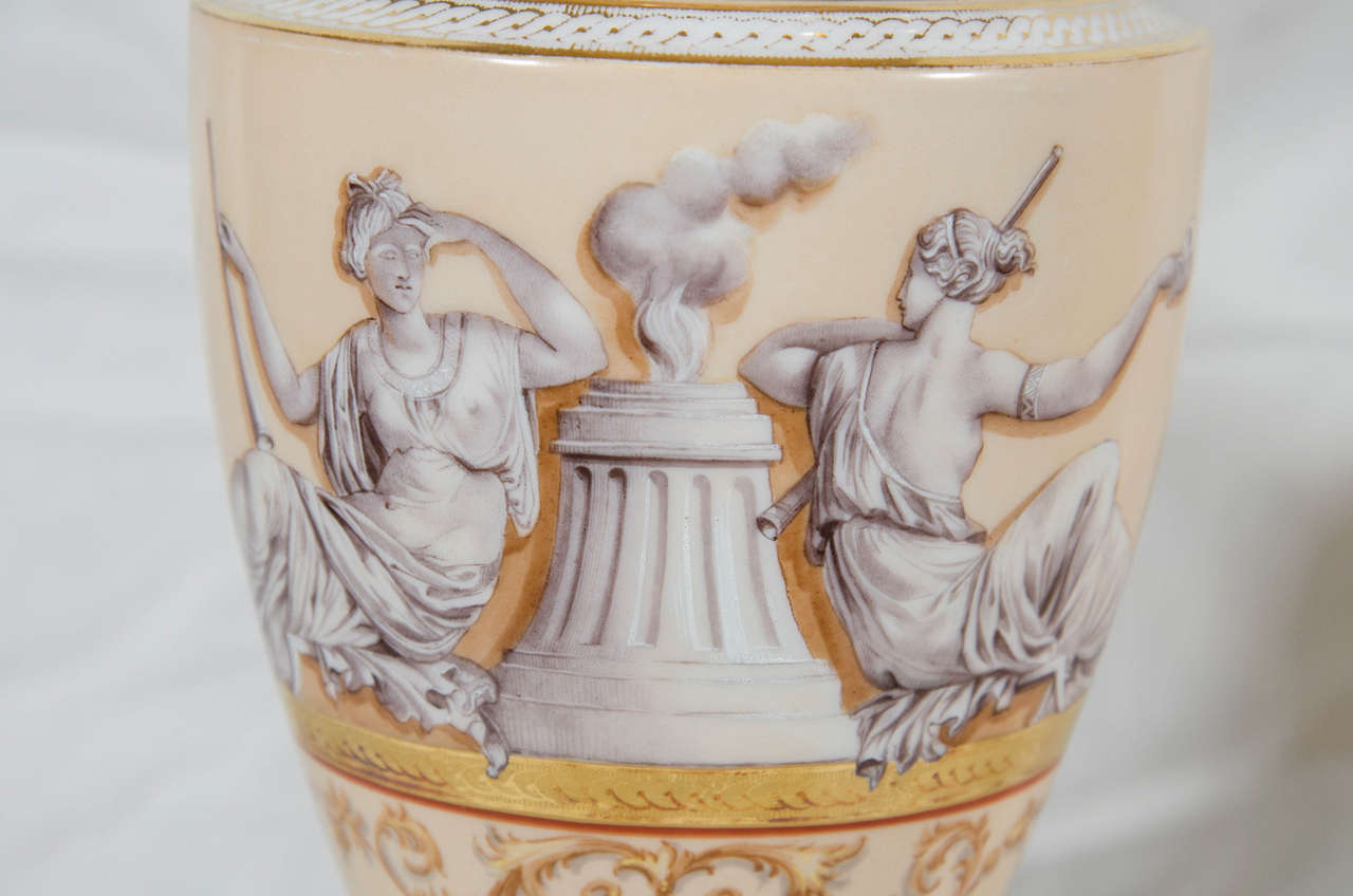 We are pleased to offer this pair of English neoclassical porcelain vases showing two women 
in classical dress. The scene is painted in grisaille supported by an elaborately gilded design. Both the neck and the foot of the vase are painted with a