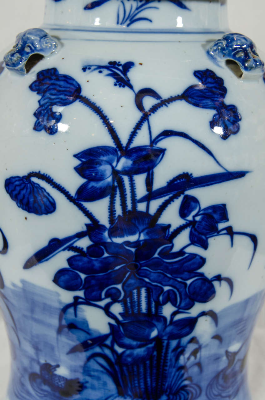 A massive Chinese Blue and White covered vase painted in varying tones of deep, underglaze cobalt. Decorated with a stylized lotus and other flowers, buds, and seedpods. In Chinese tradition a lotus symbolizes peace, harmony, and purity. The cover