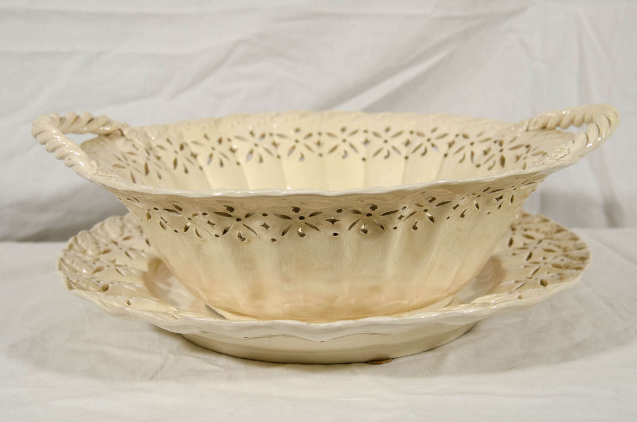An exceptionally large 18th century English creamware pottery basket and stand with reticulated decoration. The rope handles with flower and leaf terminals. Around the rim and the well of the basket are impressed acanthus leaves. The effect shows